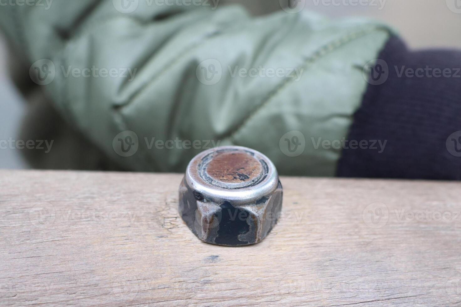 A Rusty, Worn Metal Nut Resting on an Aged Wooden Surface, Exuding Character and Charm photo
