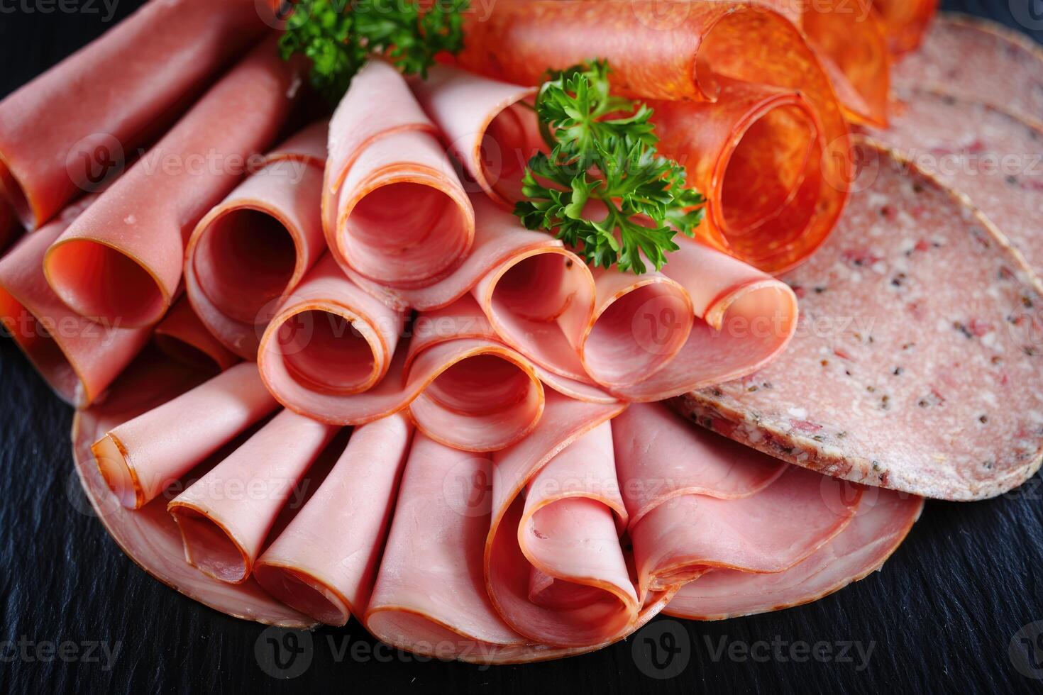 Assorted deli meats beautifully arranged on a dark serving board, ready to enjoy. photo