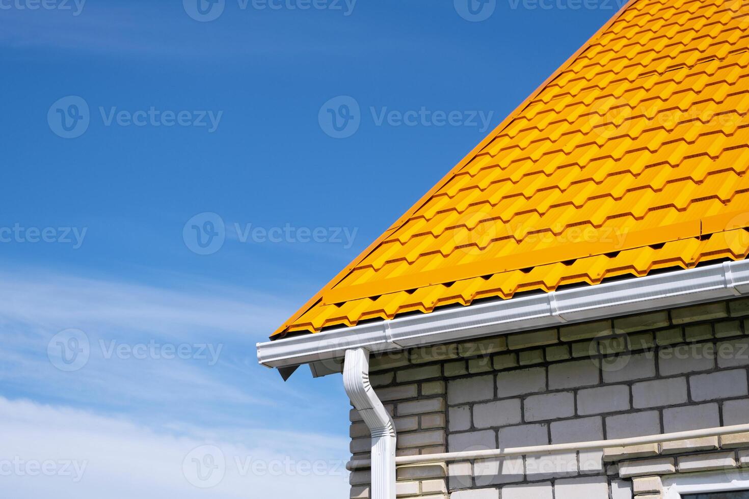 Rain Gutter Pipeline System on brick house , bright yellow metal tile roof photo