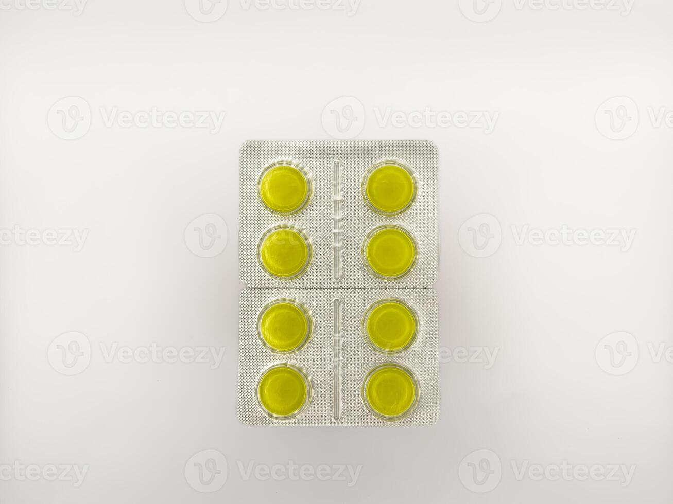 A yellow pill is on a white background. There are six pills in total. The pill is in the middle of the image, copy space, flay lay, top view photo
