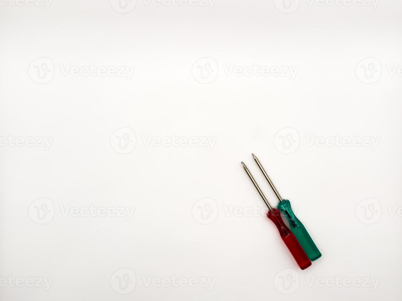 Two small colored plastic screwdrivers on a white background, red and green. copy space, flay lay, top view photo