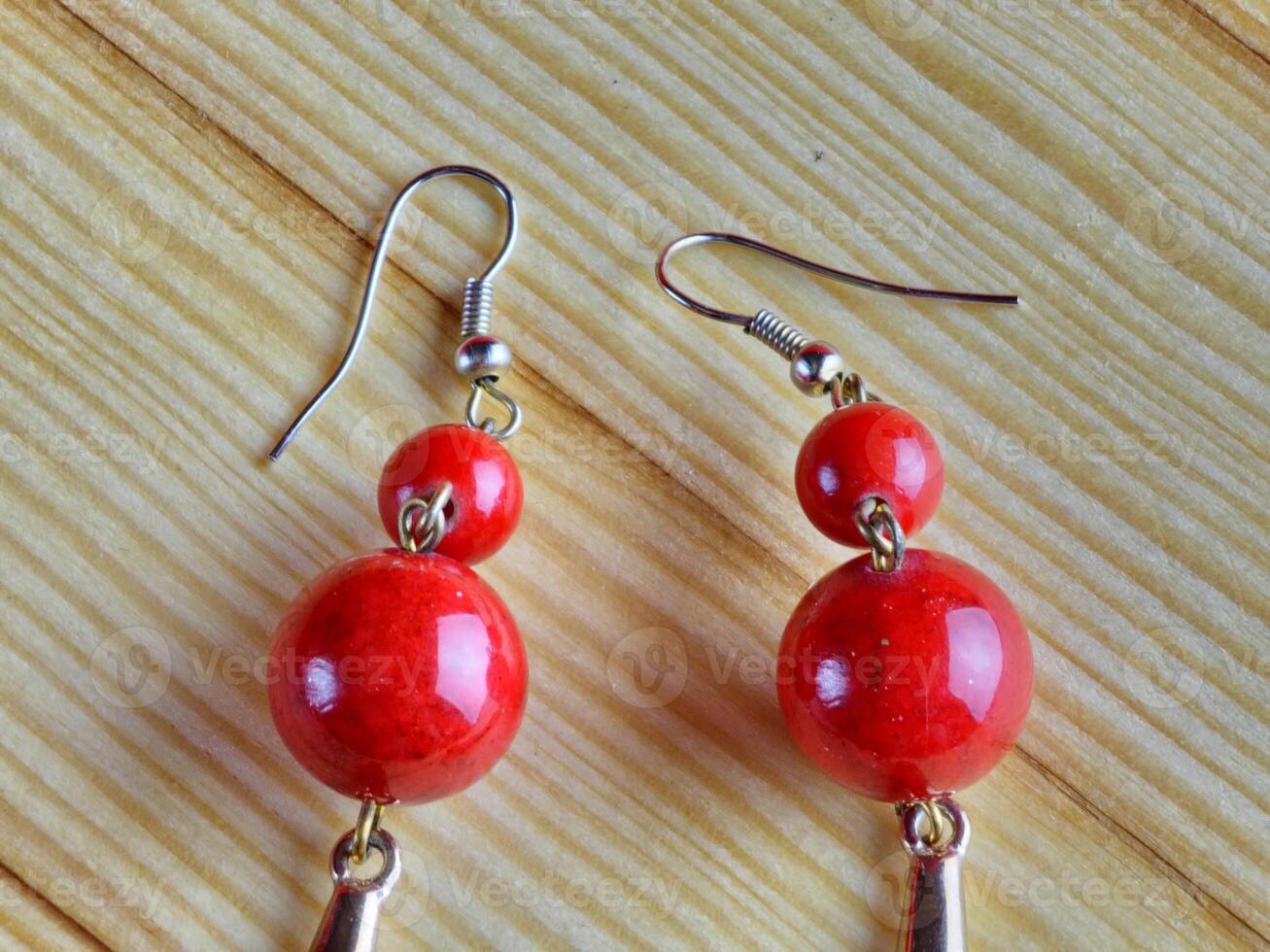 Shiny red coral earrings on a wooden background. Close-up. photo