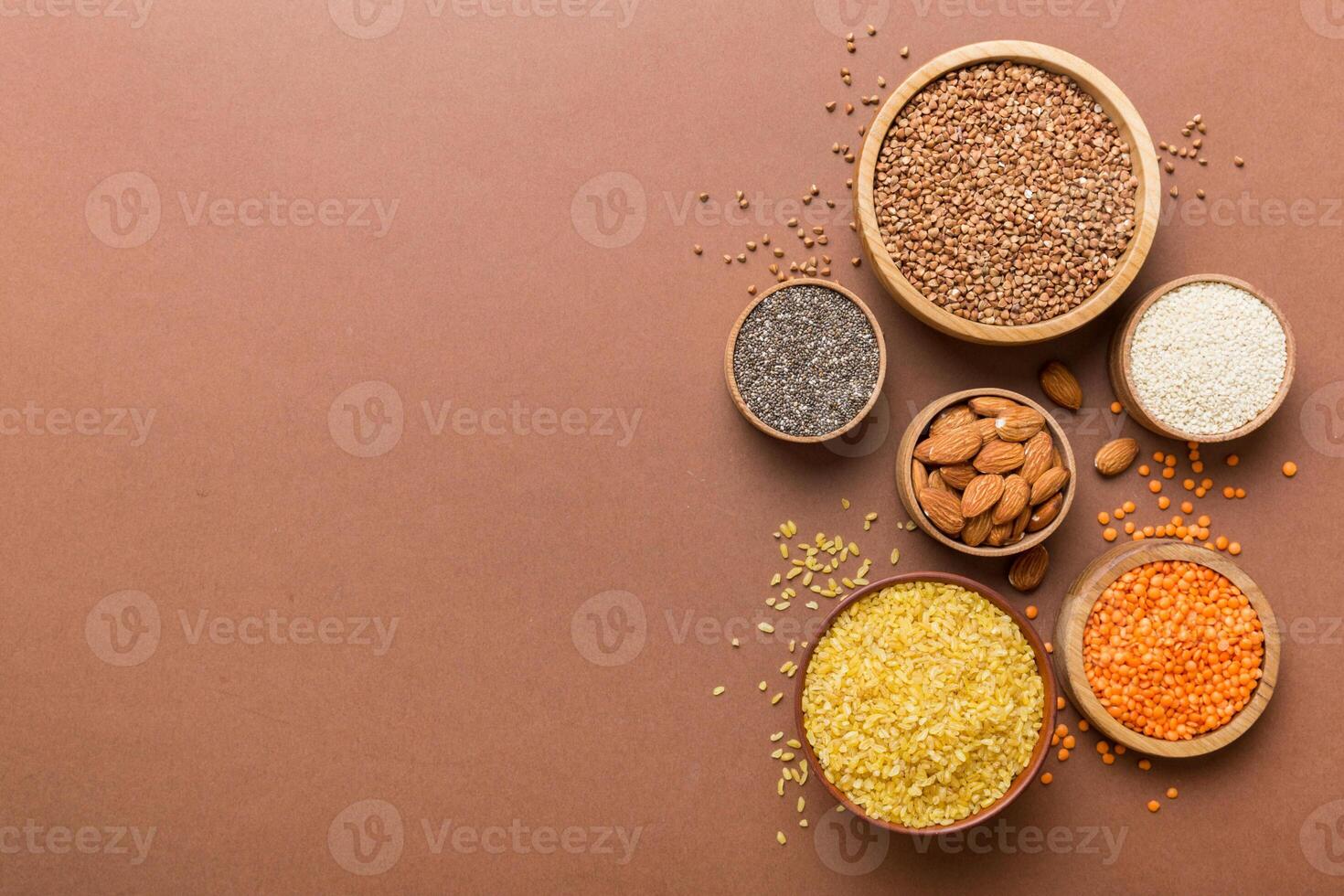Various superfoods in smal bowl on colored background. Superfood as rice, chia, quinoa, lentils, nuts, sesame seeds, almonds photo