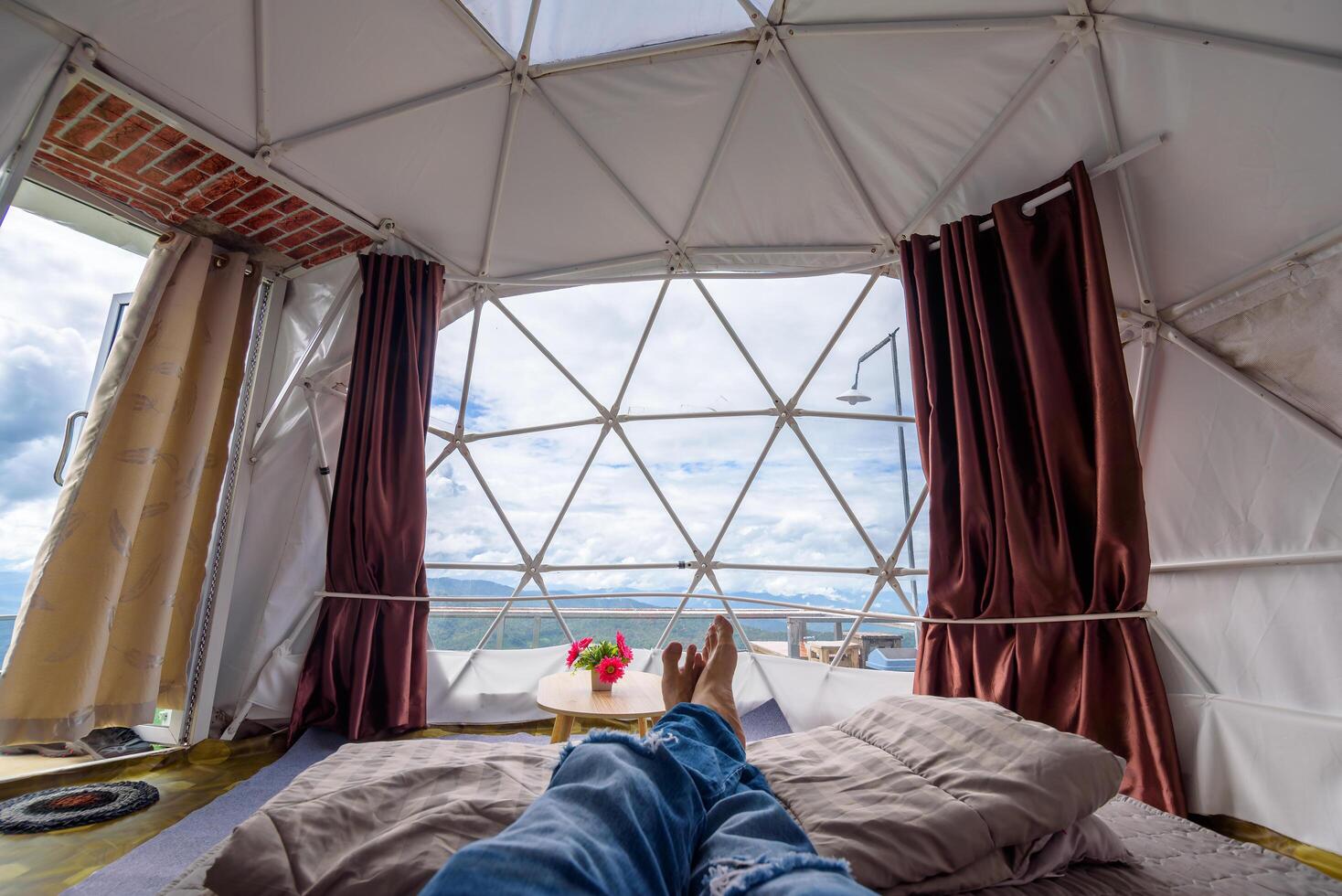 Inside of a glamping tent with man's legs in day time, Luxury camping tent for outdoor summer holiday and vacation. Lifestyle concept. photo