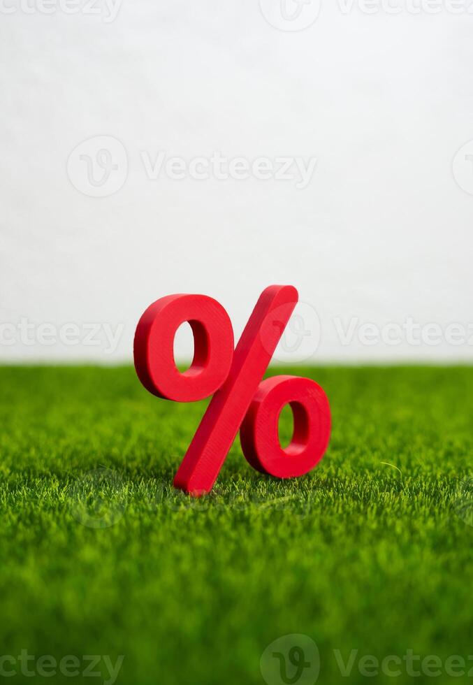 Red percent figure on green grass. Concept of a ripe and ready to collect profit on the interest rate deposit. Savings growth, or favorable financial timing. photo