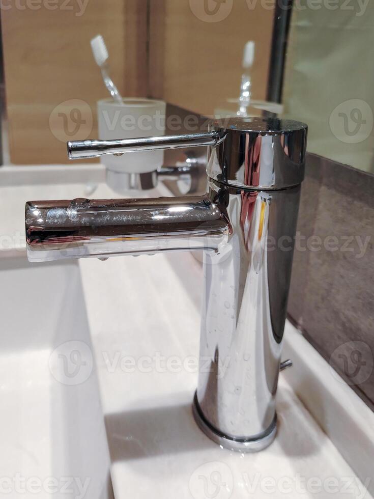 Modern chrome bathroom faucet, close-up, vertical photo