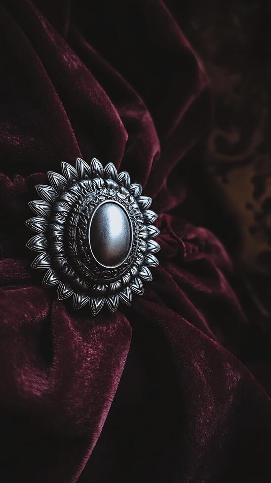 Ornate Silver Brooch on Deep Burgundy Velvet Fabric. A close up image showcasing intricate detail. photo
