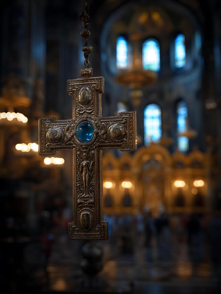 Ornate Religious Cross Hanging in a Church Interior. A detailed close up of an intricately designed golden cross with a blue gemstone, set against a softly blurred background of a church's interior. photo