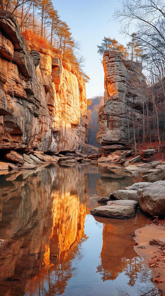 Serene Autumn Reflection in a Sandstone Gorge. Golden sunlight illuminates the cliffs and trees, perfectly mirrored in the tranquil water below. photo