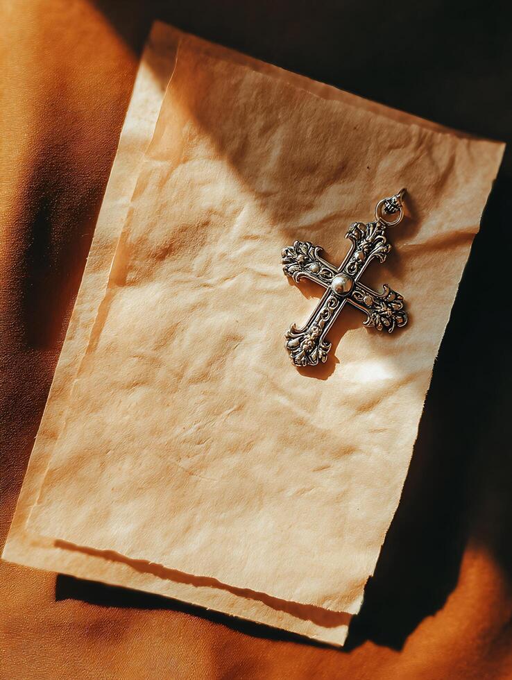 Ornate Silver Cross on Aged Paper, Spiritual Still Life Photography. photo