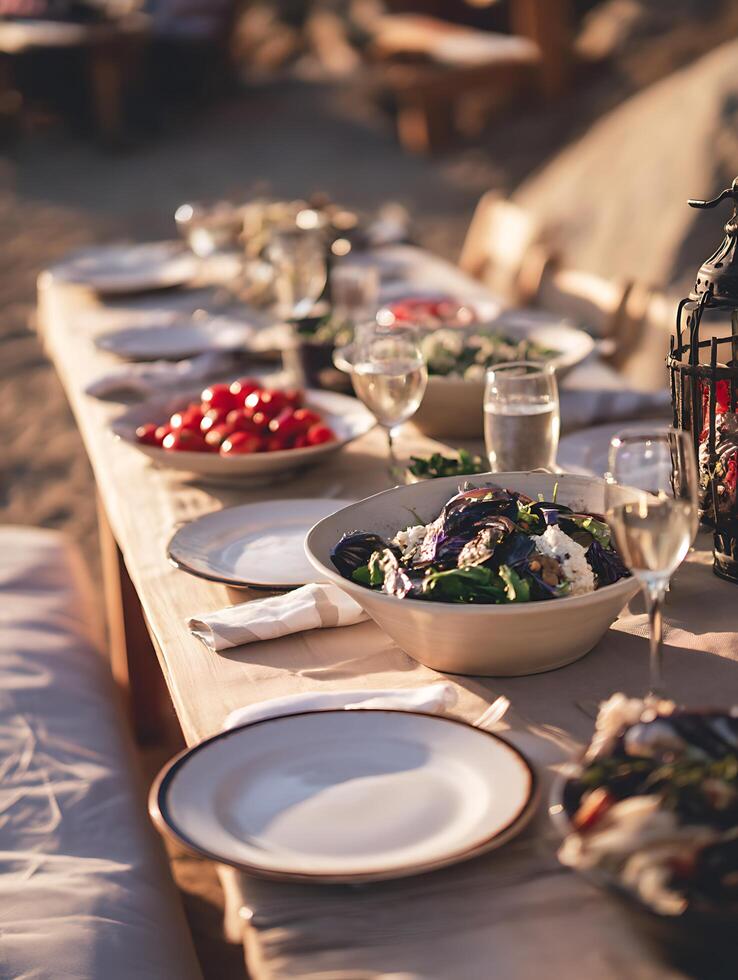 Outdoor Dinner Party Table Setting at Sunset. A close up view of a beautifully arranged table with fresh salads and other dishes, perfect for summer or spring gatherings. photo