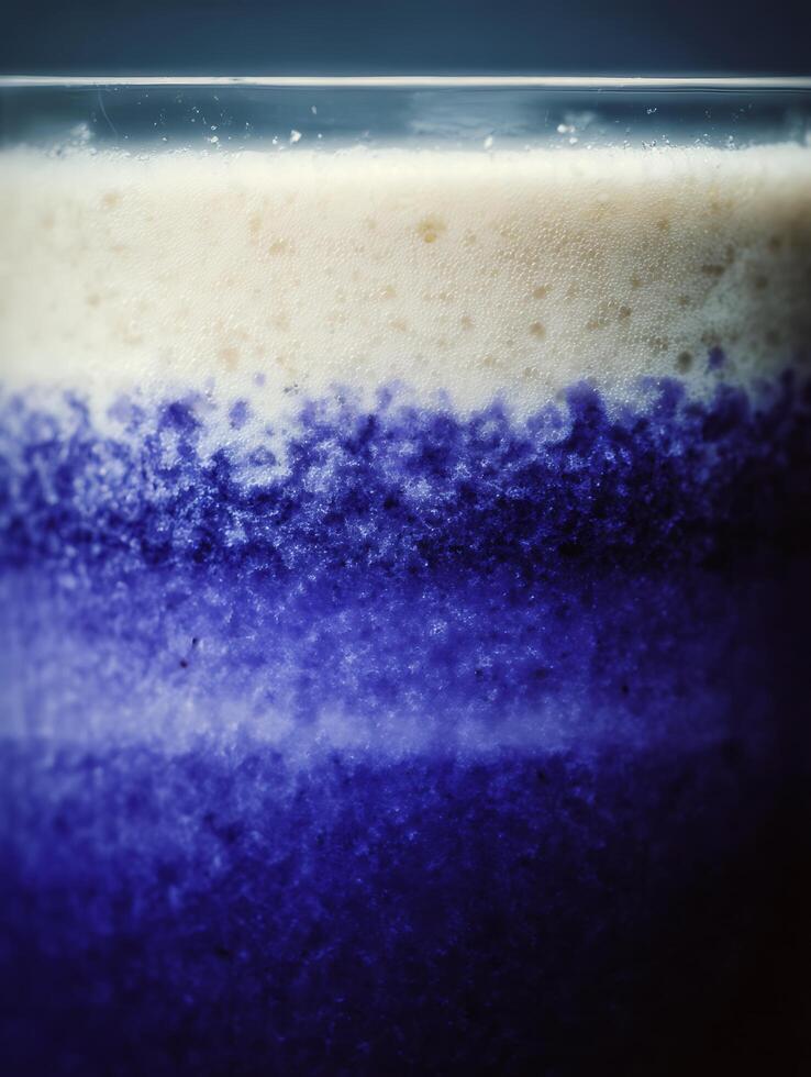 Close up of a layered beverage with creamy top and deep blue bottom. A textured image ideal for backgrounds or food and drink publications. photo