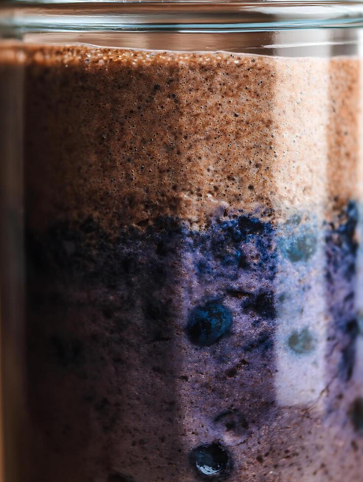Close up of a layered blueberry and chocolate smoothie in a glass jar. photo