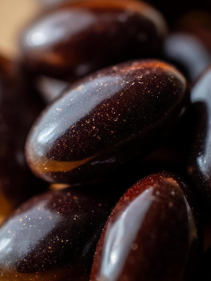 Close Up of Shiny Dark Brown Oval Objects, Possibly Candies or Pills. photo
