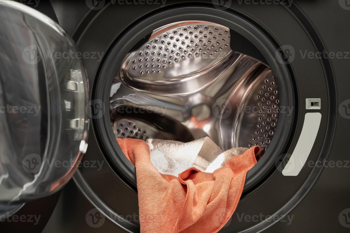 Dirty wet towels in front load washing machine drum interior close up showing laundry and cleaning concept photo