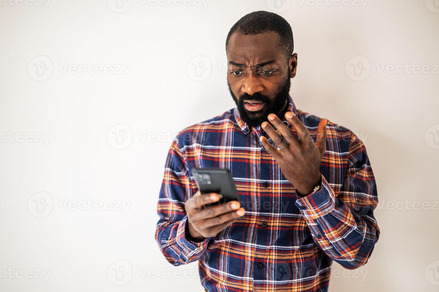 Portrait of a black man showing confusion and frustration while messaging and explaining something on a smartphone call. photo