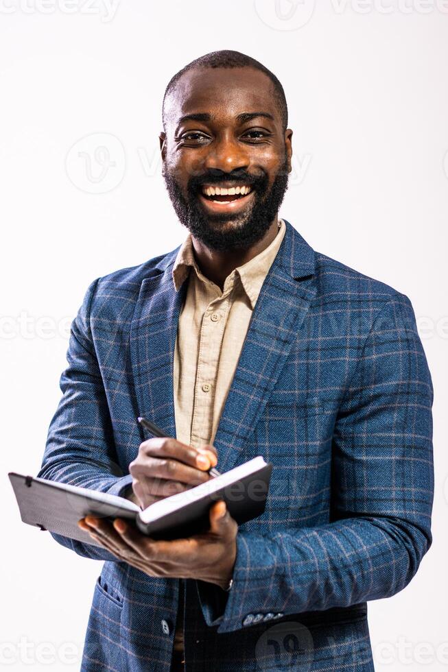 Studio shot of a handsome African American businessman with a beard, smiling broadly as he writes in his planner. photo