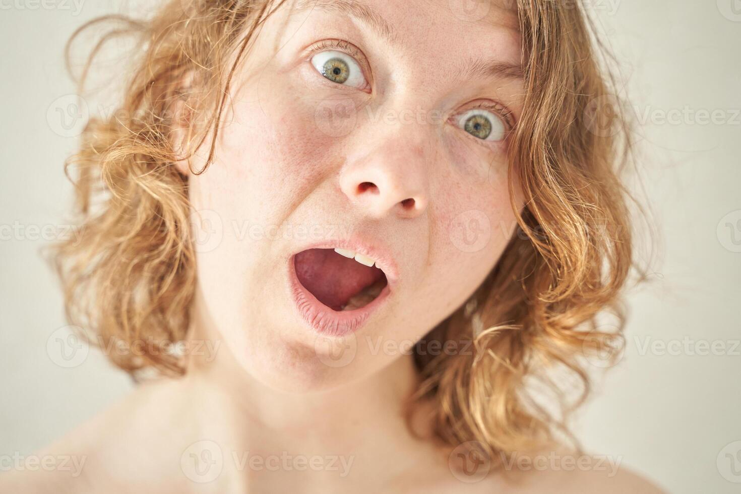 Caucasian female with curly hair showing surprised expression close-up portrait. photo