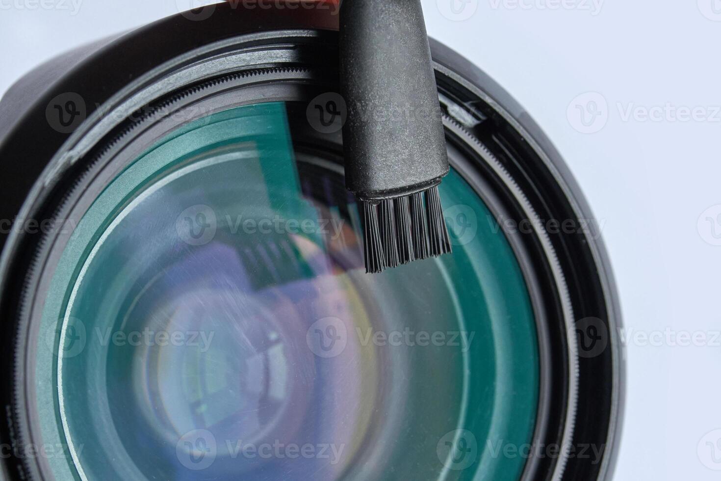 Close up of camera lens with cleaning brush on transparent surface with reflection. photo