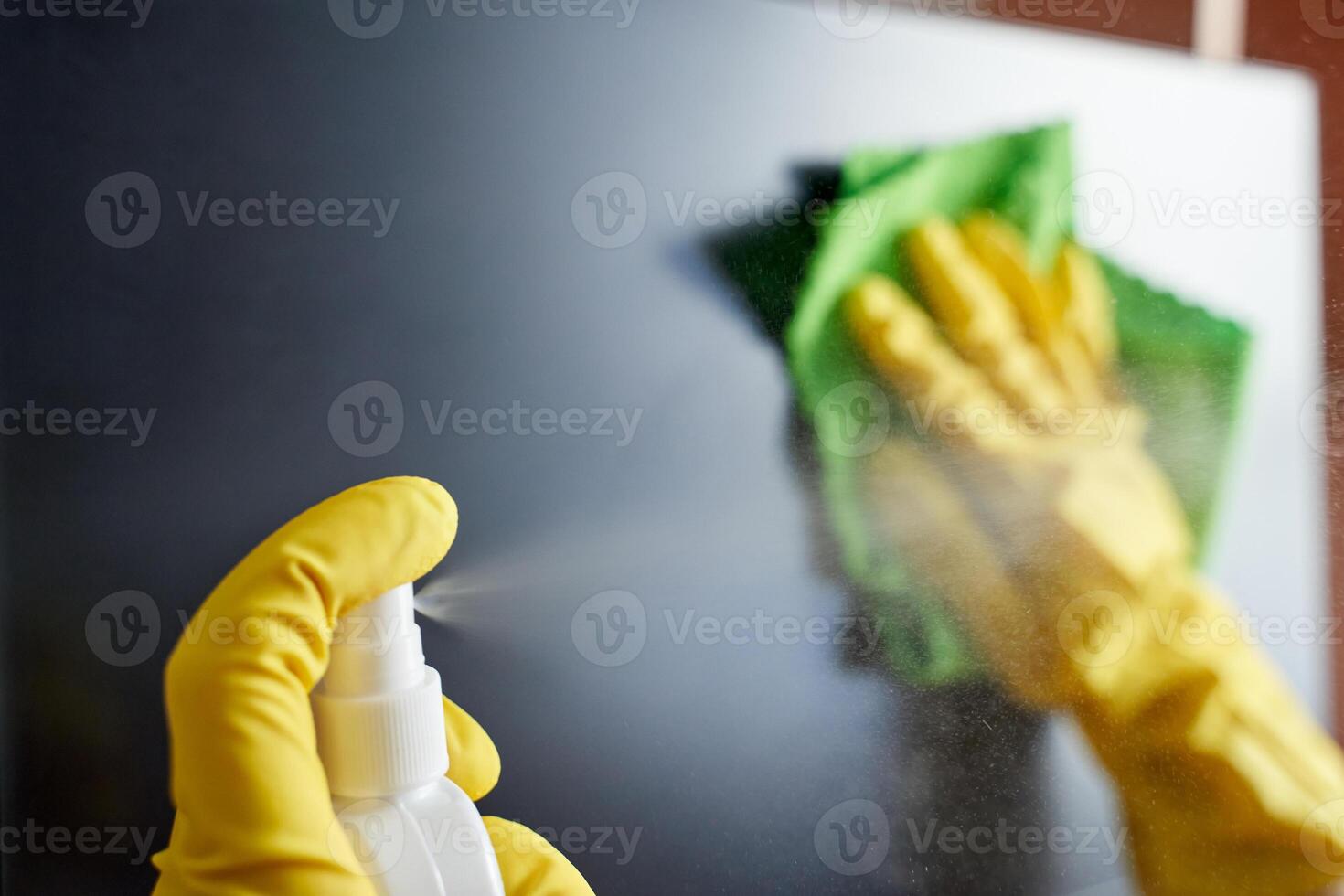 Close up of gloved hands cleaning screen with spray bottle and cloth for a streak free surface. photo