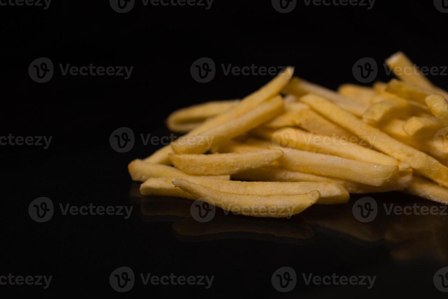 Crispy golden french fries piled on a dark reflective surface, symbolizing quick delicious indulgence, classic fast food, or a savory snack option photo