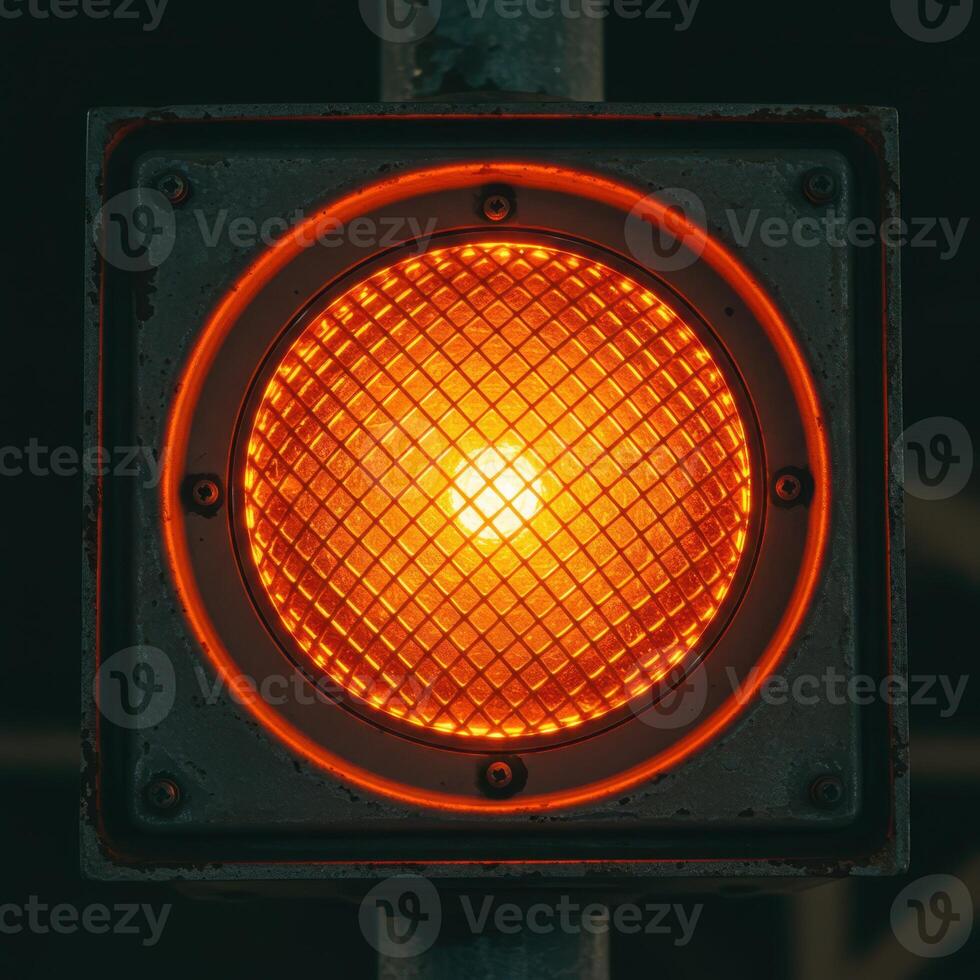 Close up of a single glowing orange traffic signal light with a textured lens photo