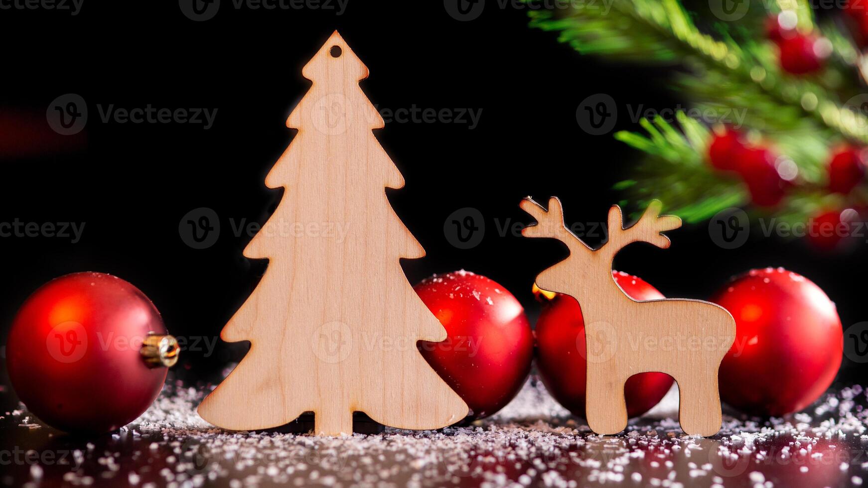 Wooden toy deer and spruce on a dark table with white snow photo
