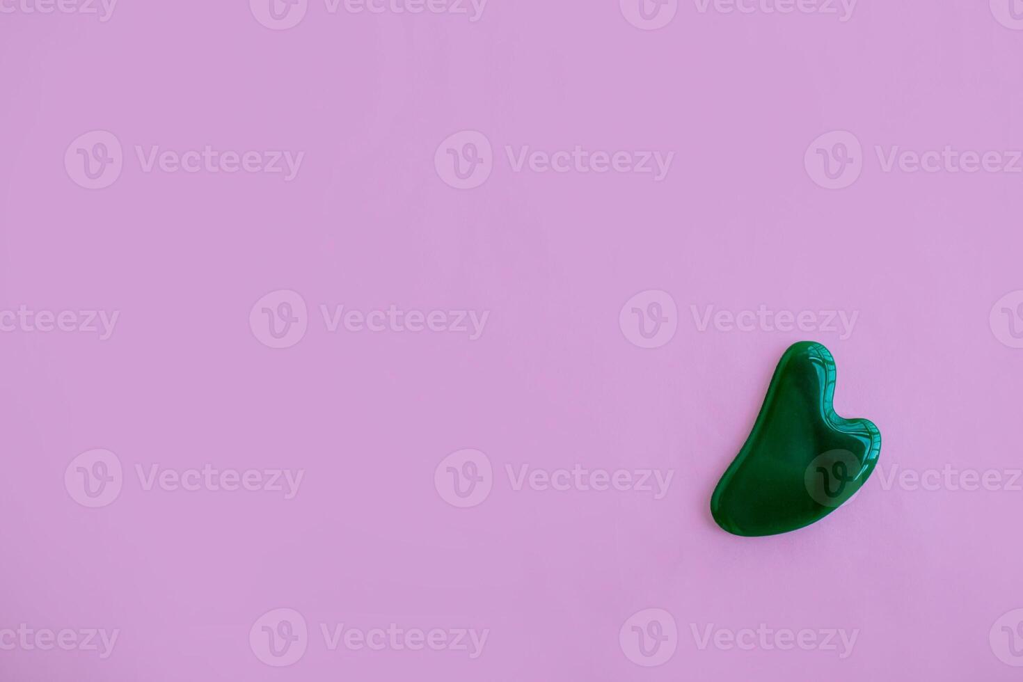 Jade massager on a pink background. Background with copy space. photo
