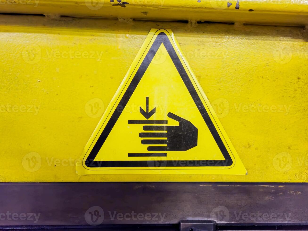Yellow Safety Warning Sign Indicating Hand Hazard on Industrial Equipment photo