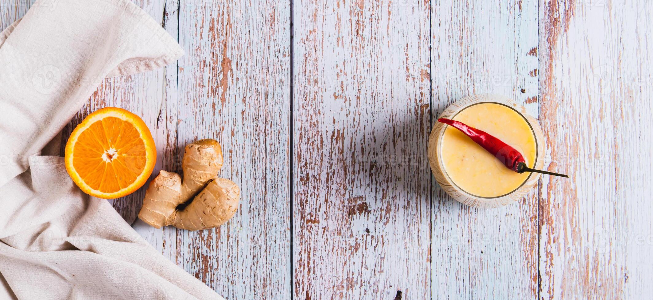 Orange ginger smoothie with pepper for weight loss in a glass top view web banner photo