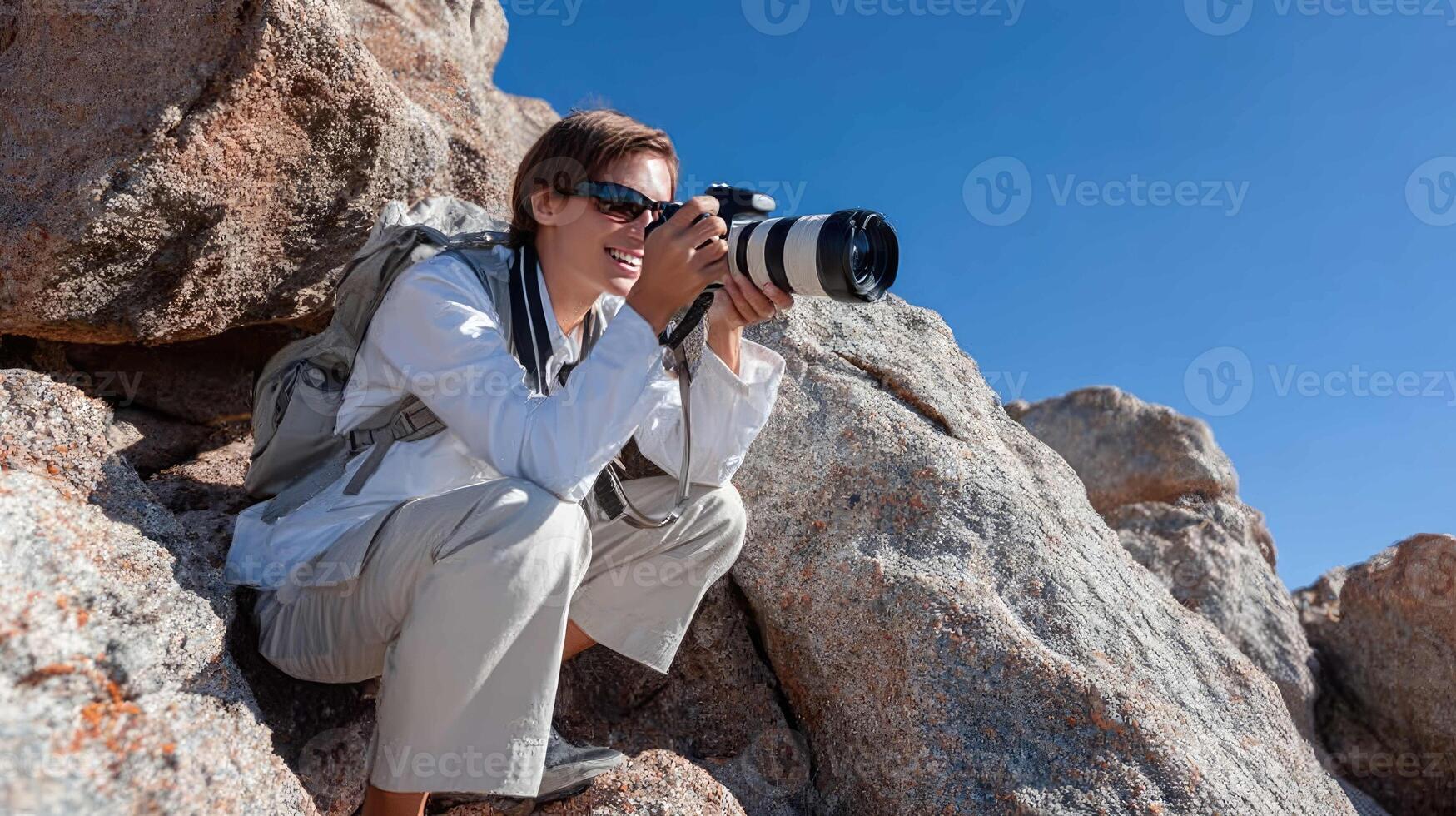 A woman with a camera on a rock photo