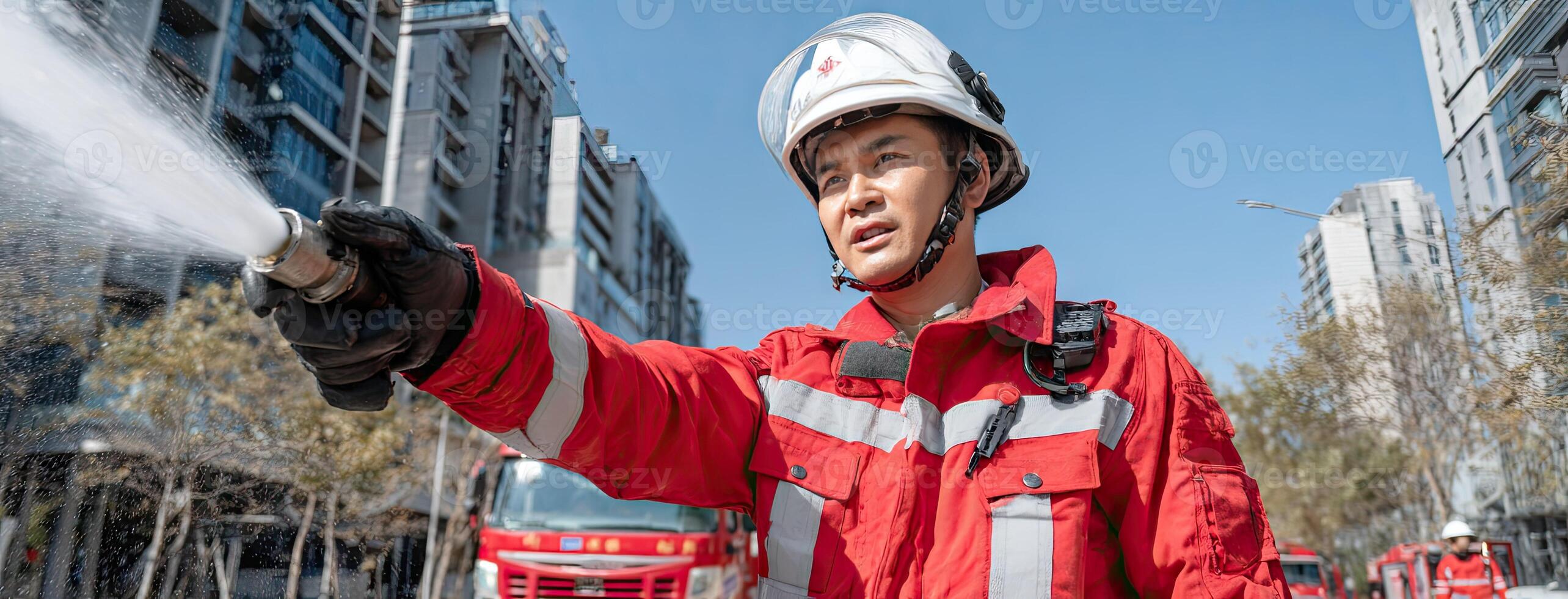 A firefighter in a red uniform spraying water photo