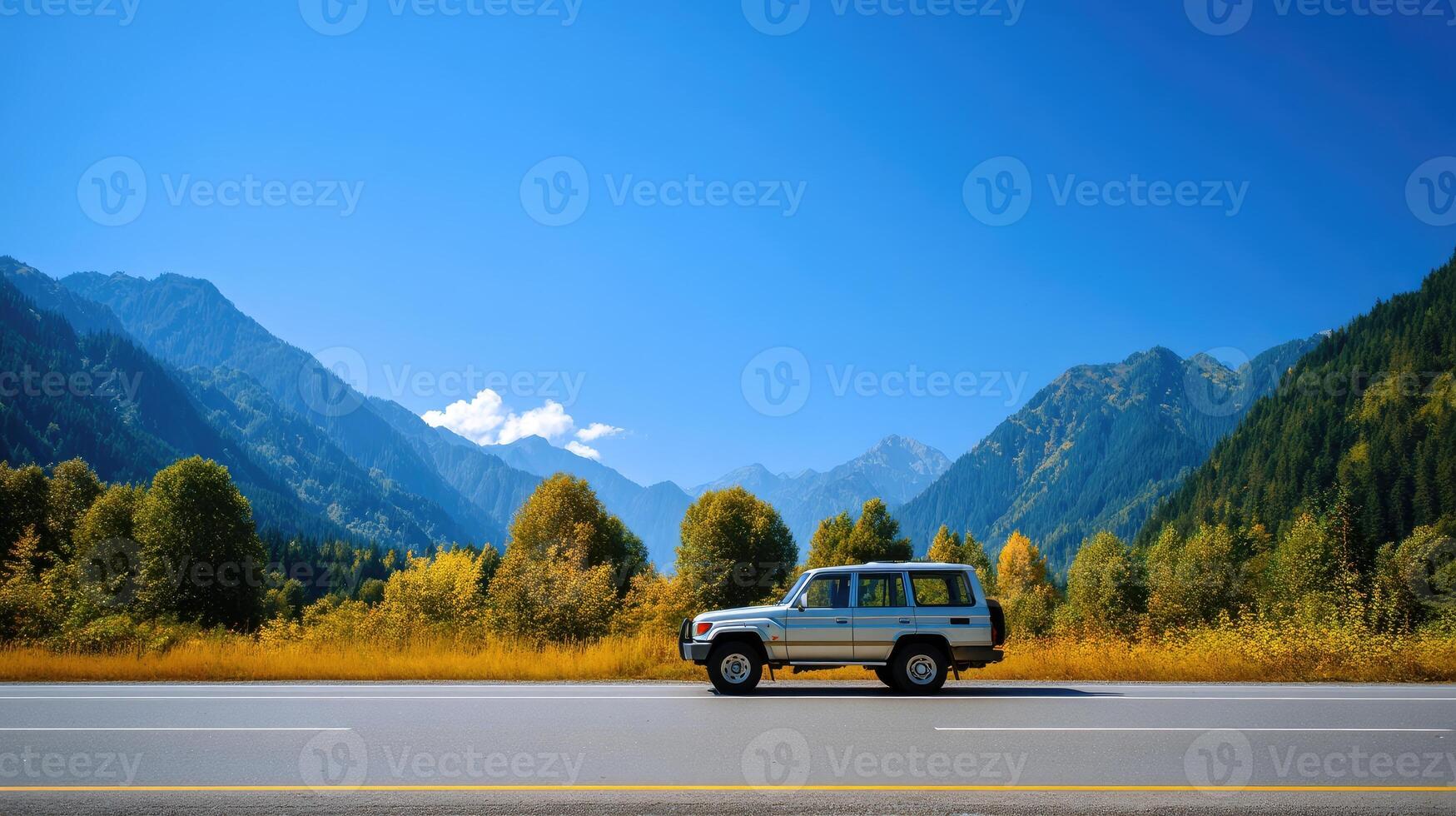 A car is driving down the road in front of mountains photo