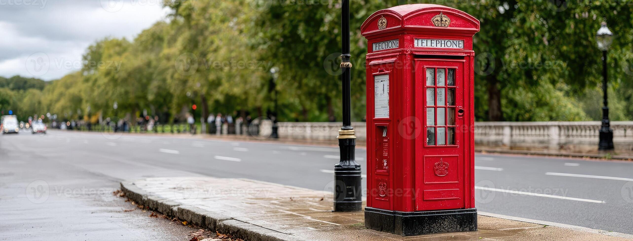 A red telephone box is sitting on the side of the road photo