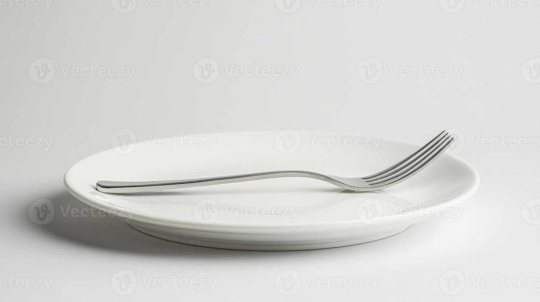 Fork resting on empty white plate on white background photo