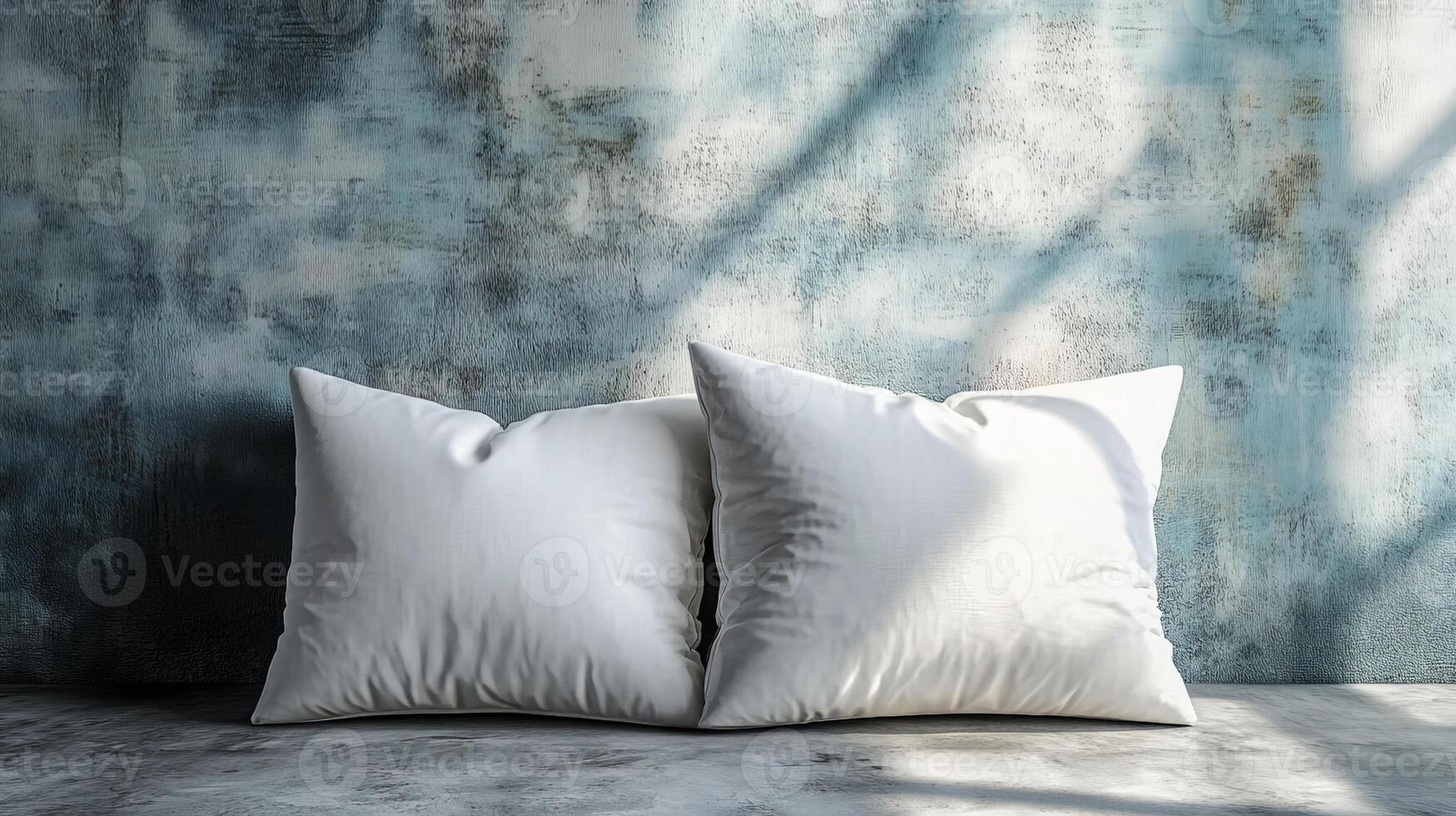 Two white pillows resting on concrete surface against textured wall photo