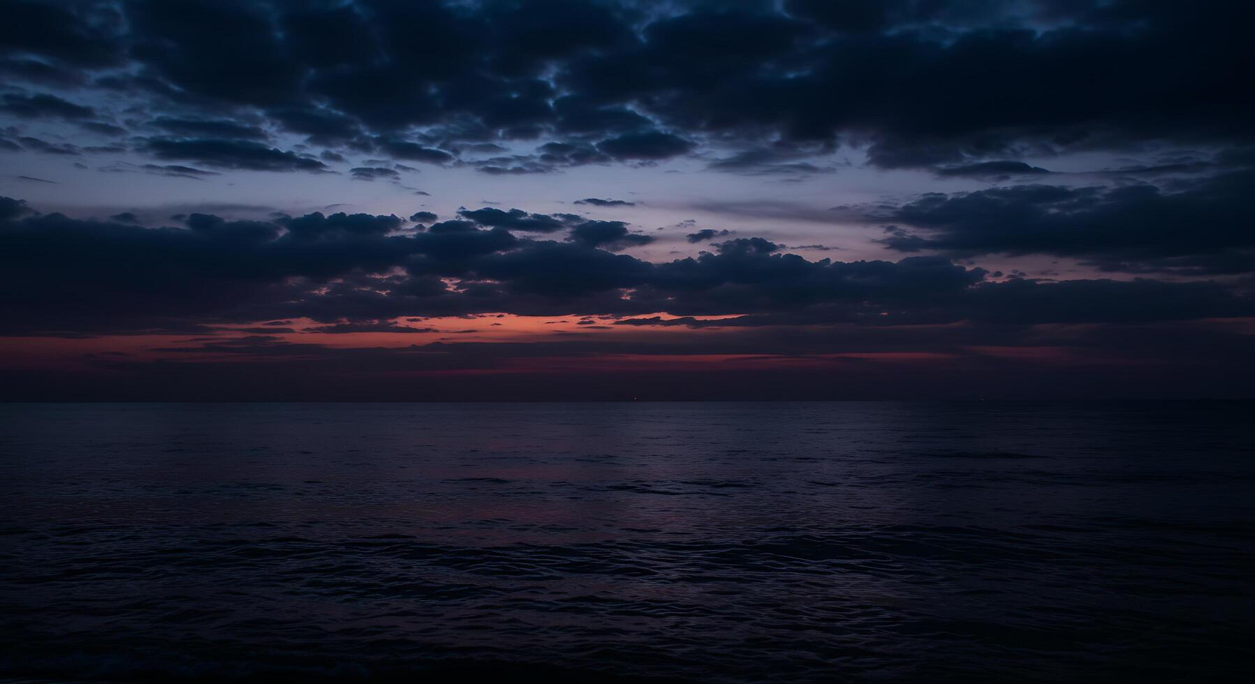 A dark sky over the ocean at sunset photo