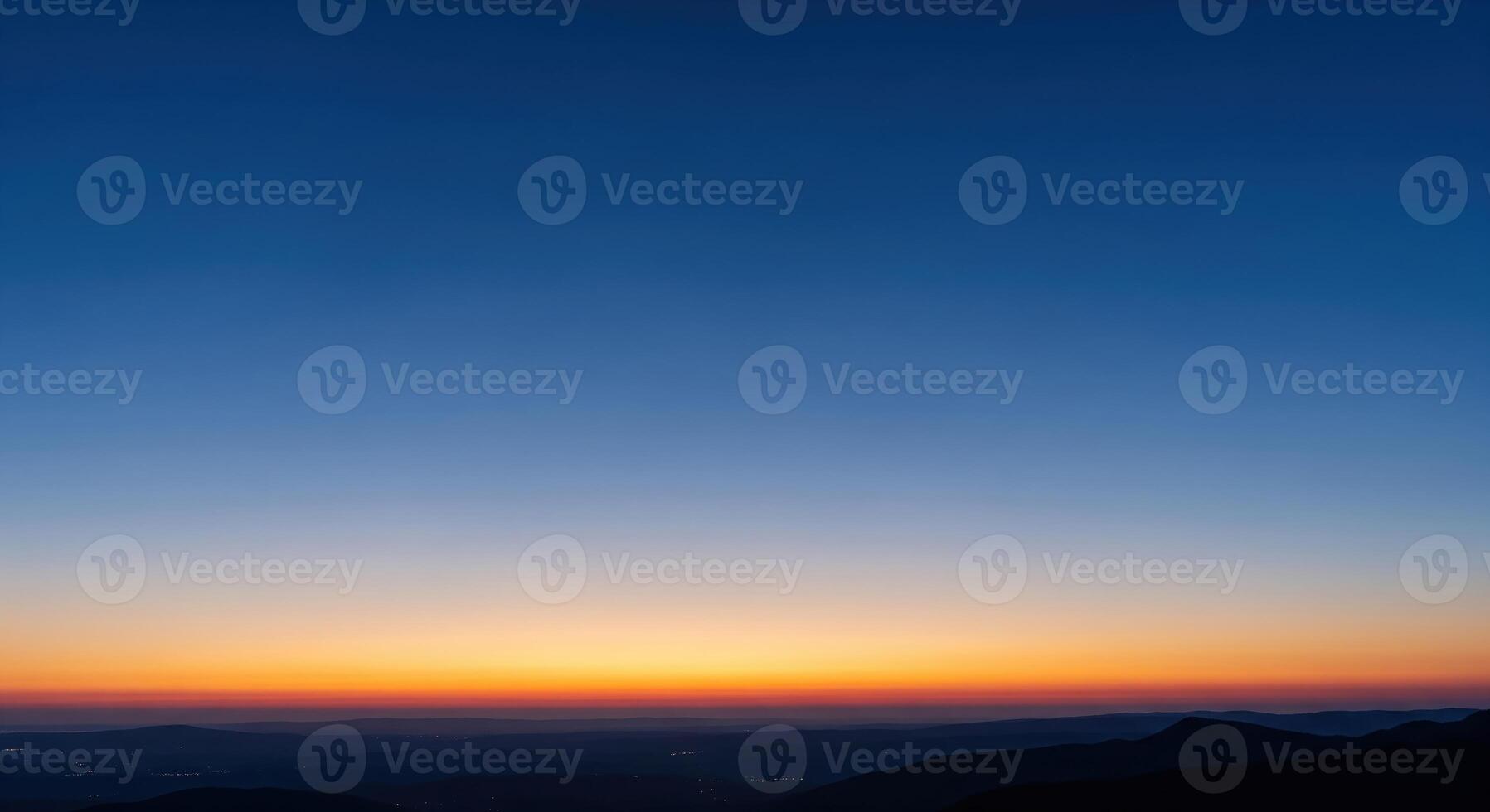 A sunset over the mountains with a blue sky photo