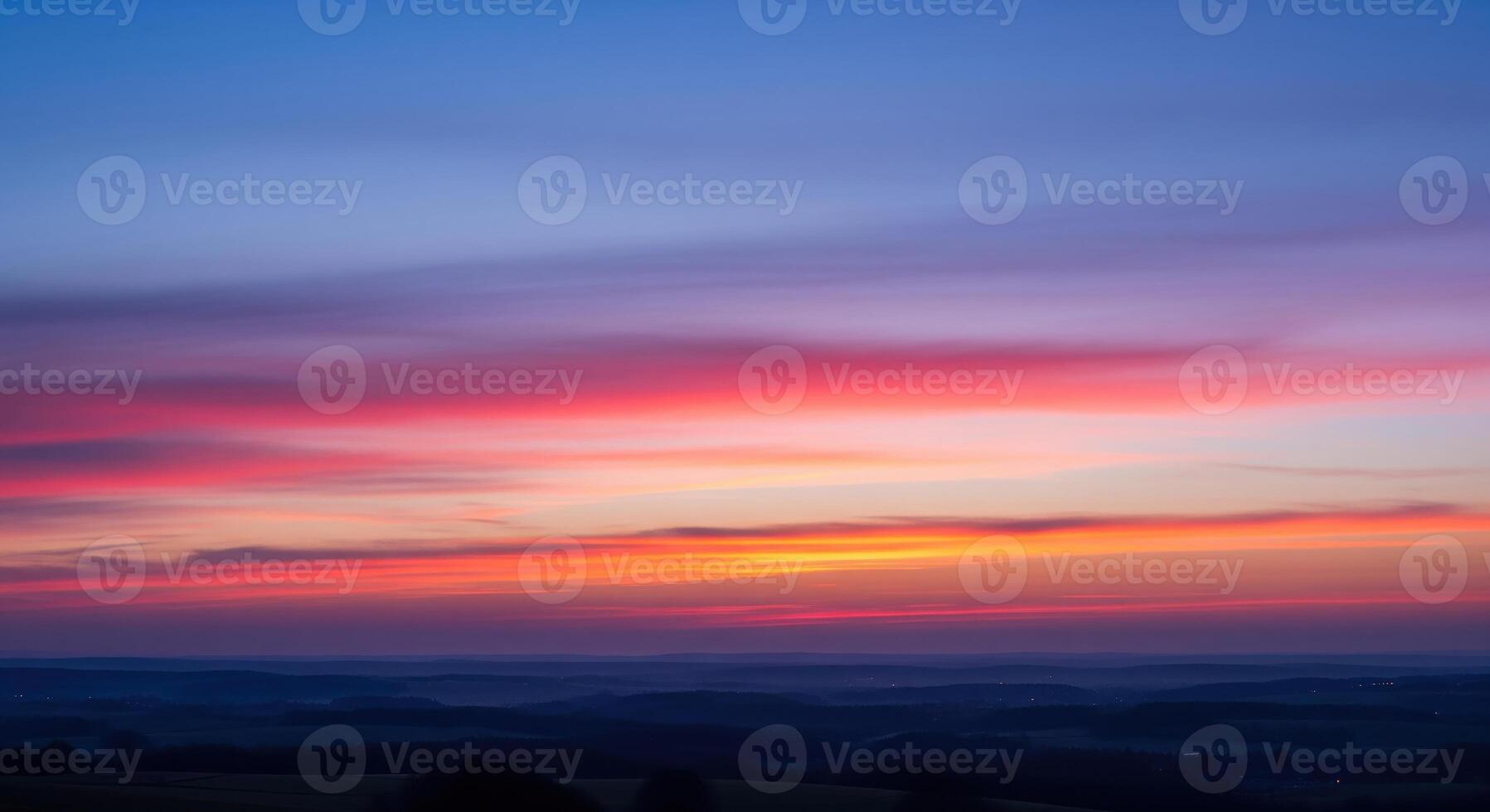 A sunset over the countryside with a blue sky photo