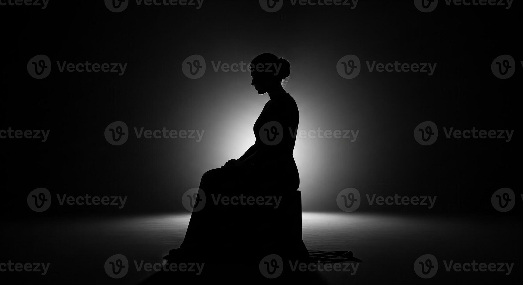 Silhouette of a woman sitting on a chair in the dark photo