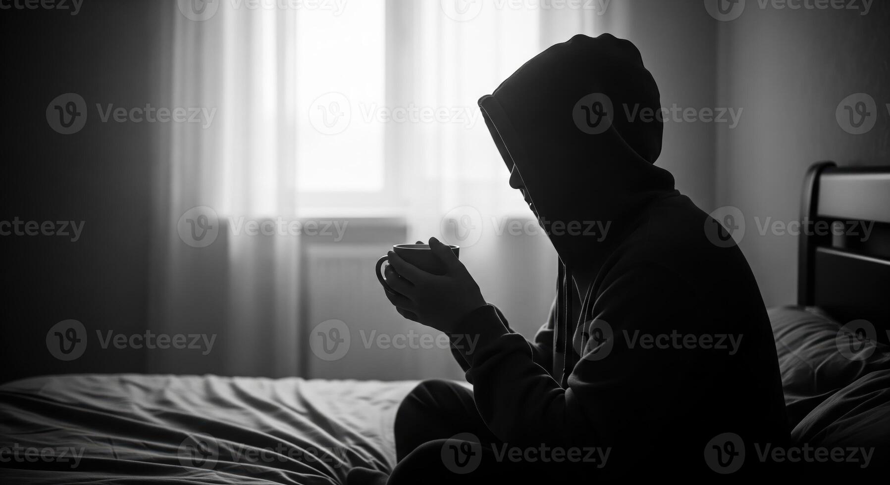 A person in a hoodie sitting on a bed photo