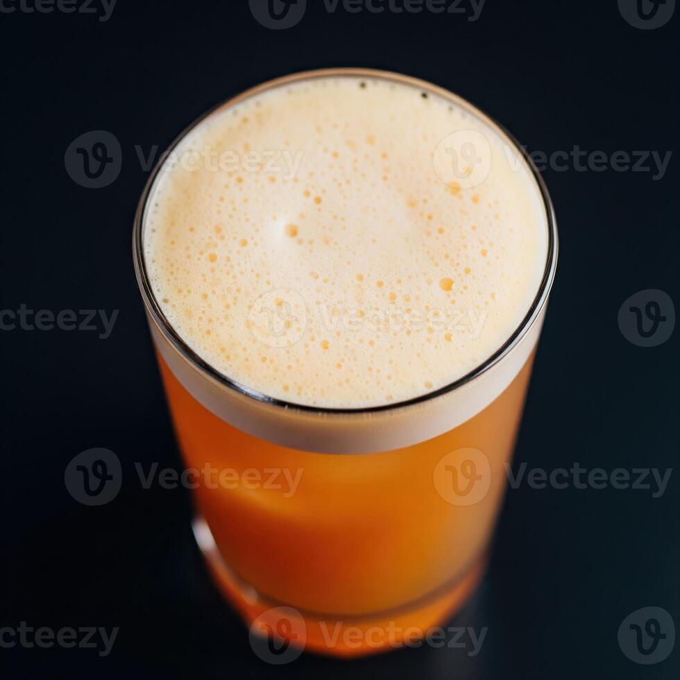 A glass of orange drink sitting on a black surface photo