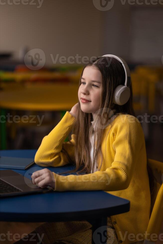 Girl with headphones studying at a desk photo
