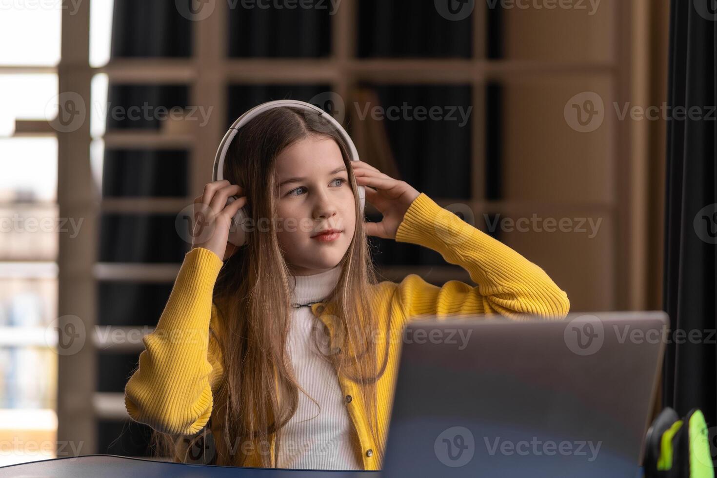 Schoolgirl learning with headphones laptop and notebook in calm digital environment. studies at home with a laptop and notebook illustrating hybrid learning confidence, self-organization and modern photo