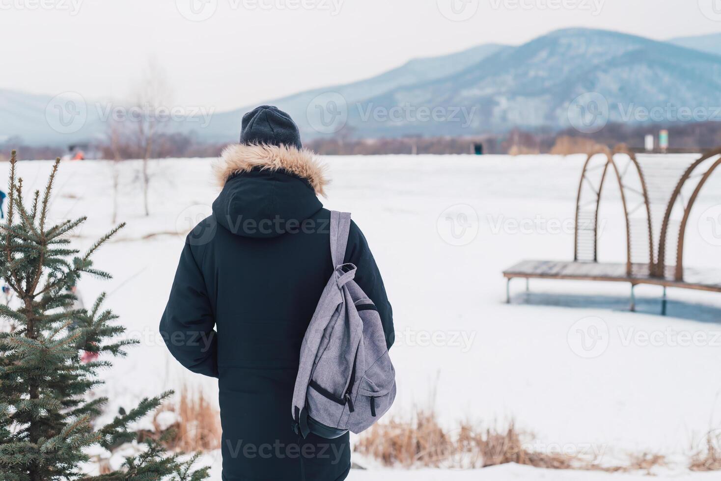 Young man solo traveler standing alone with backpack on the winter background. photo