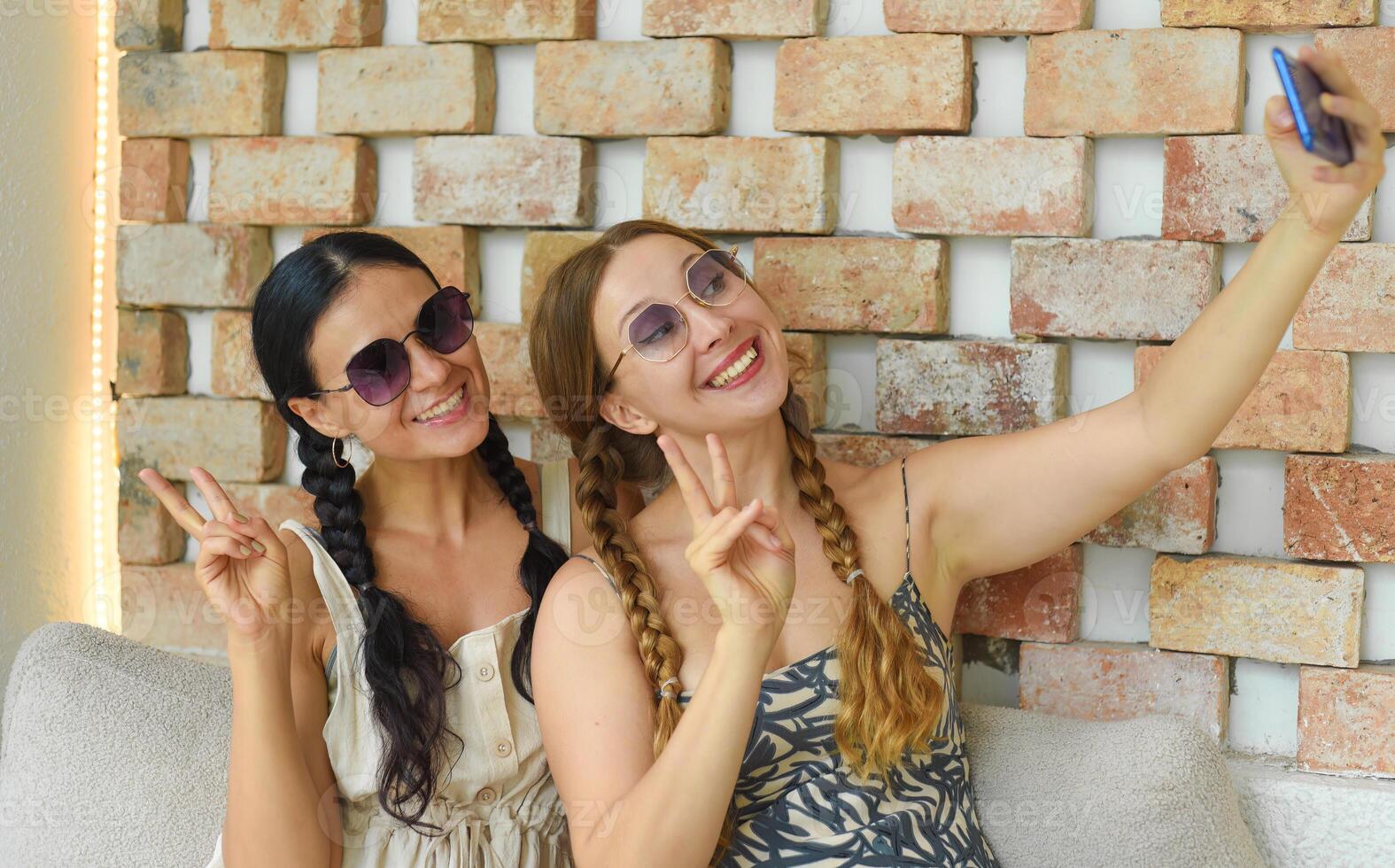 Ukrainian woman and Russian woman together with braids posing and taking a selfie photo
