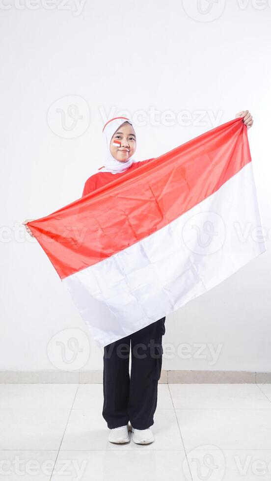 Beautiful Asian girl celebrate Indonesia independence day in red and white outfit holding Indonesian flag isolated on white background photo