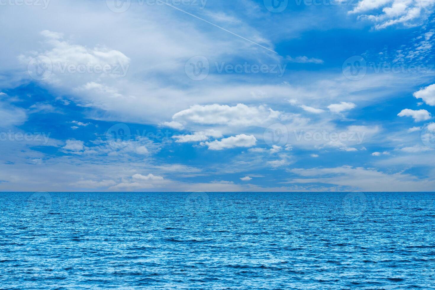 Enjoy the calm of the ocean beneath a bright blue sky with fluffy clouds. This peaceful seascape embodies tranquility and natural beauty, ideal for relaxation and inspiration. photo