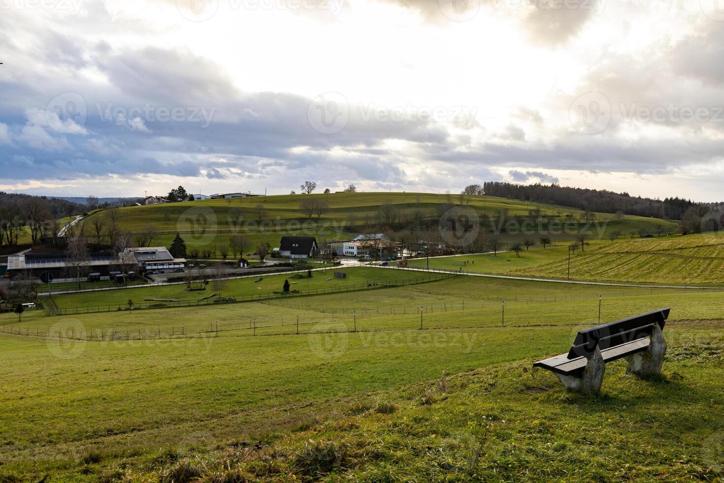Bench on a hill near a village in sunlight photo