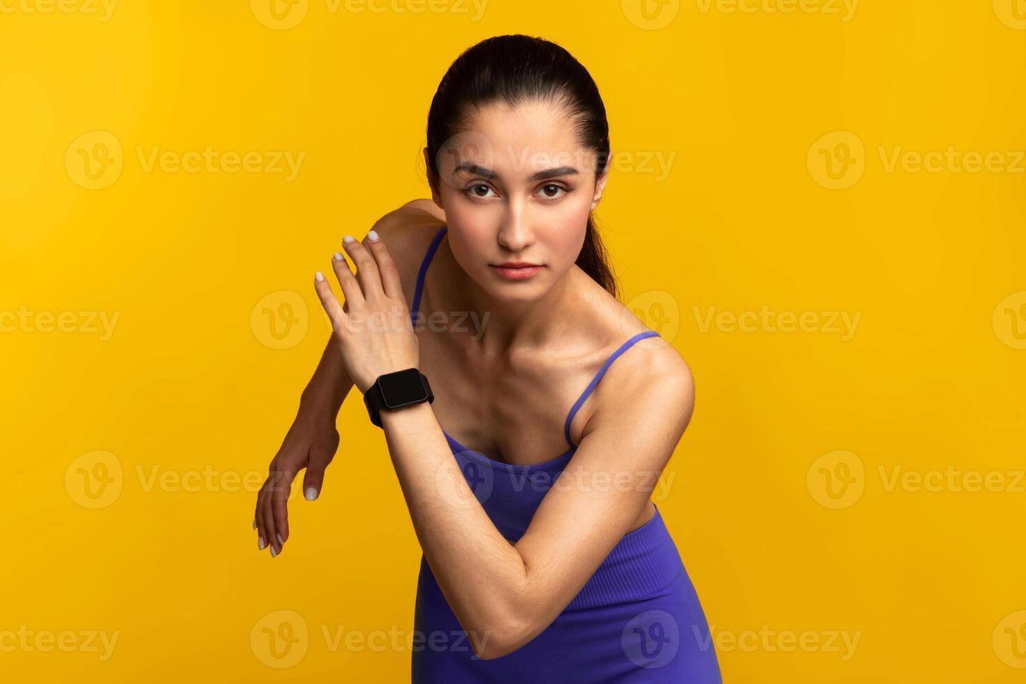 Cardio Workout And Competition Concept. Portrait of sporty young lady running towards camera. Determined woman wearing fitness tracker ready for sprint, jogging isolated on orange studio background photo